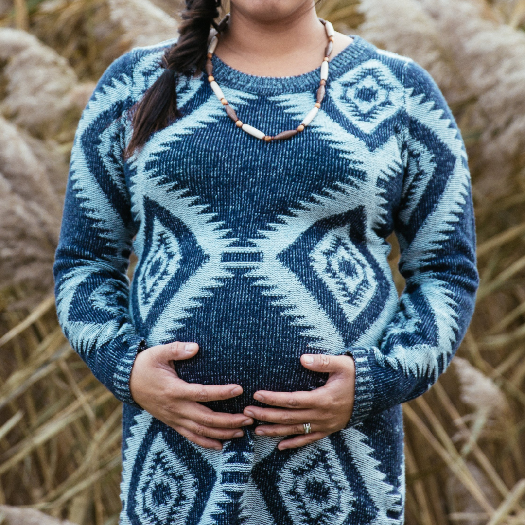 Pregnant woman in blue dress holding her belly